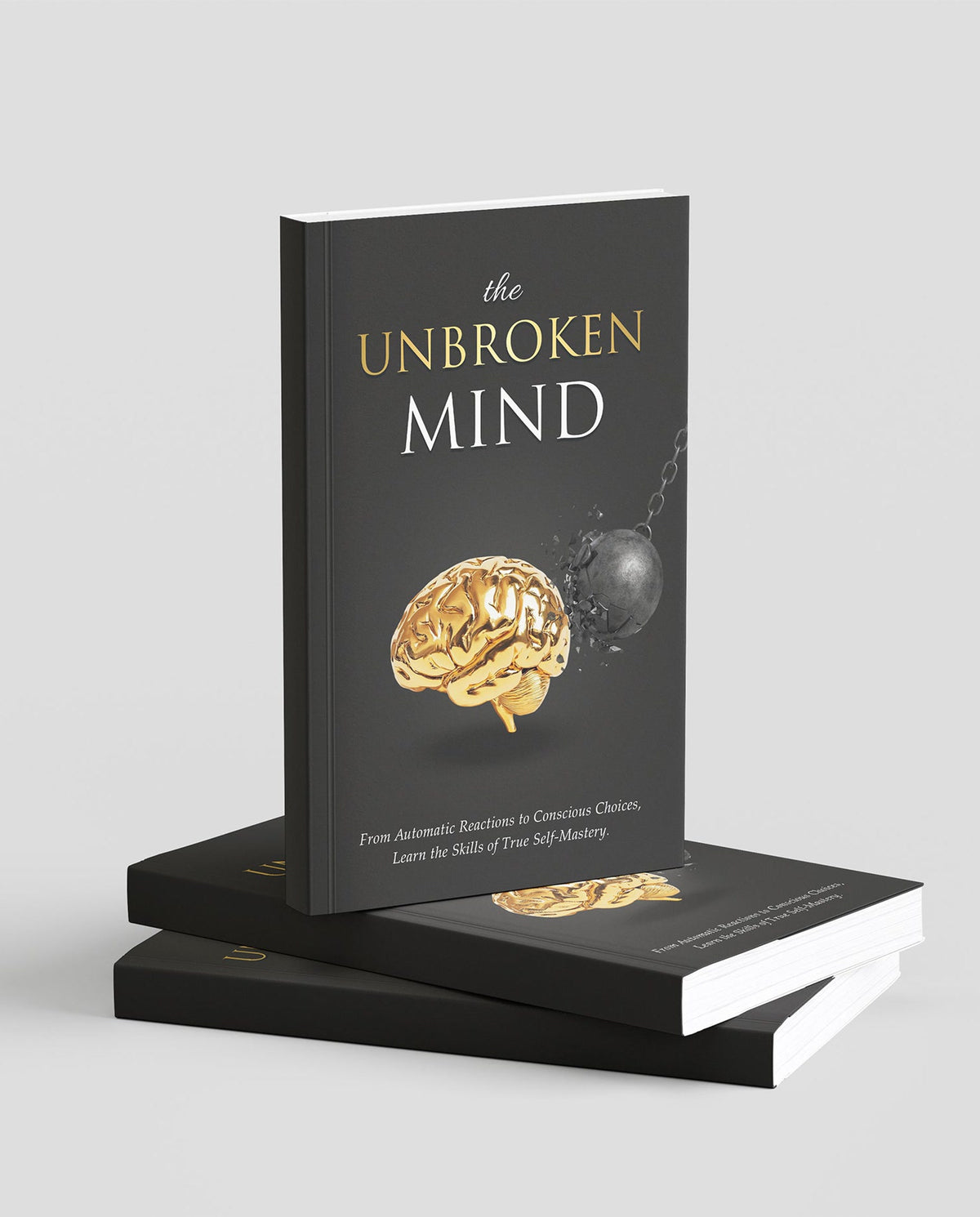 The Unbroken Mind System printed book standing on a stack of copies, gold brain on a black cover