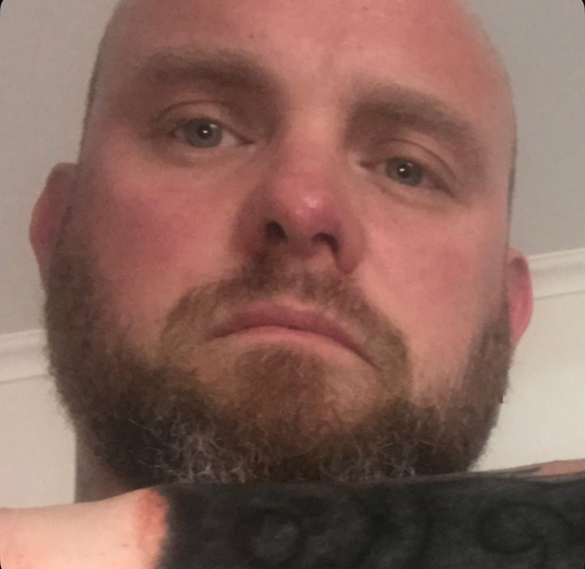 Close-up of a bearded face looking straight into the camera, lying down.